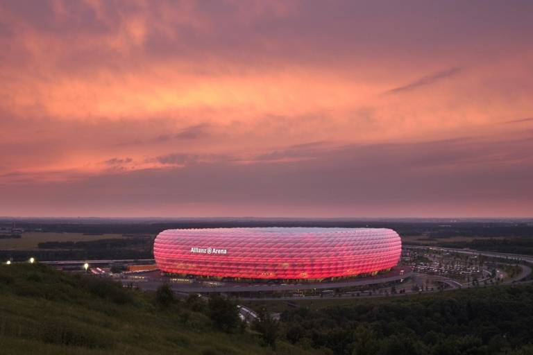 The Allianz Arena in Munich illuminated in red at sunset.