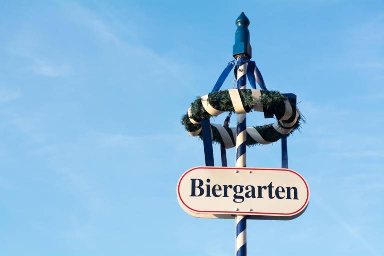 A sign on top of a maypole in Munich that has the word beer garden on it. 