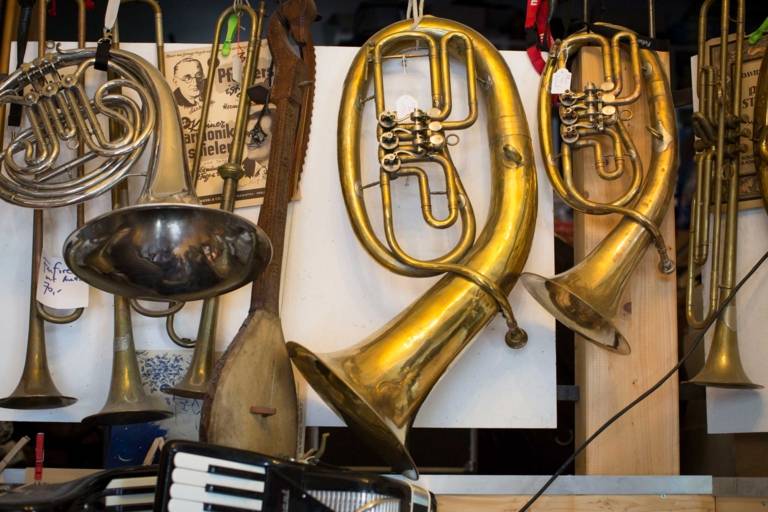Several wind instruments hang side by side in a music shop