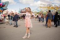 A woman who is wearing a dirndl is smiling at the Oktoberfest in Munich.
