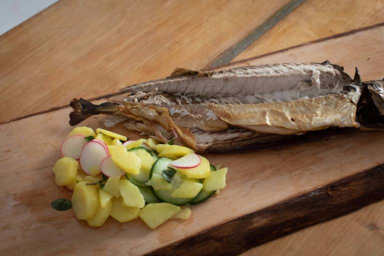 A portion of fish with potato salad, nicely arranged on a wooden board.
