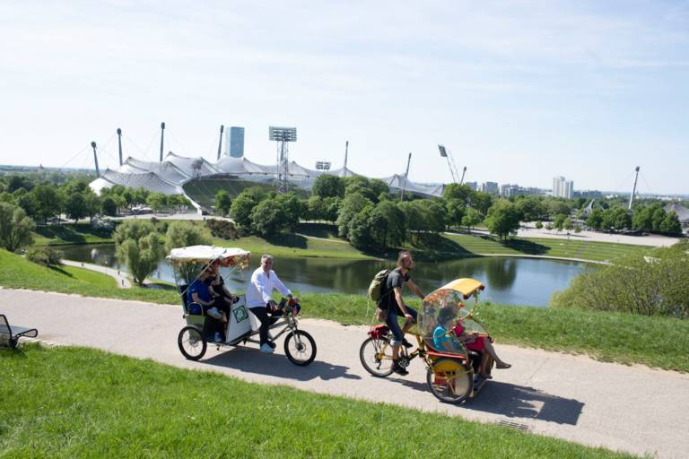 A man drives his rickshaw and guests through the Olympic Park in Munich.