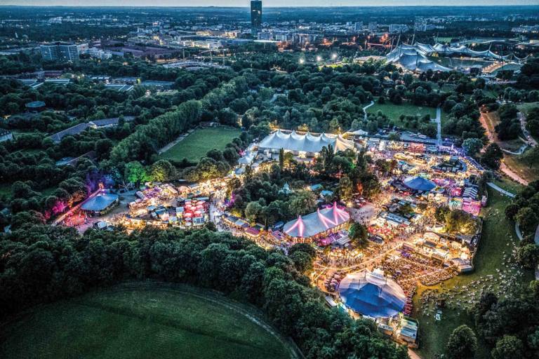 The Munich 极速赛车 Summer Tollwood Festival in the Olympiapark photographed from above with a drone at nightfall.