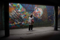 Young woman stands before a mural in Munich.
